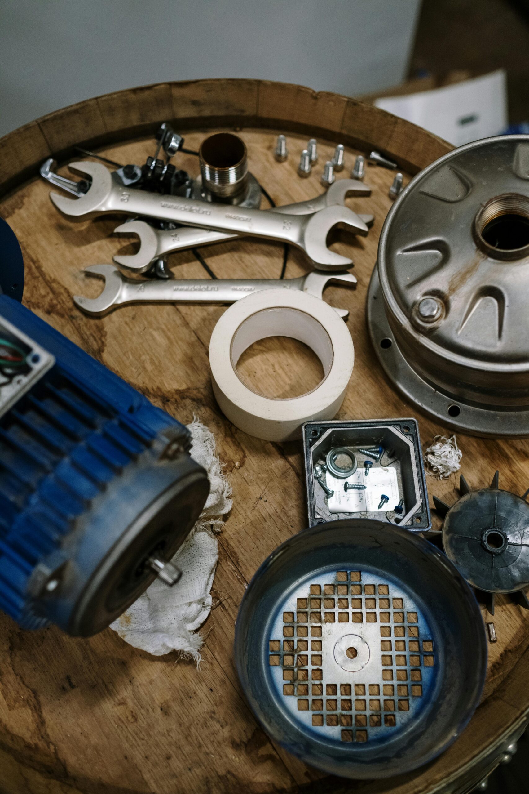 Top view of mechanical parts and tools arranged on a wooden table for repair and assembly.
